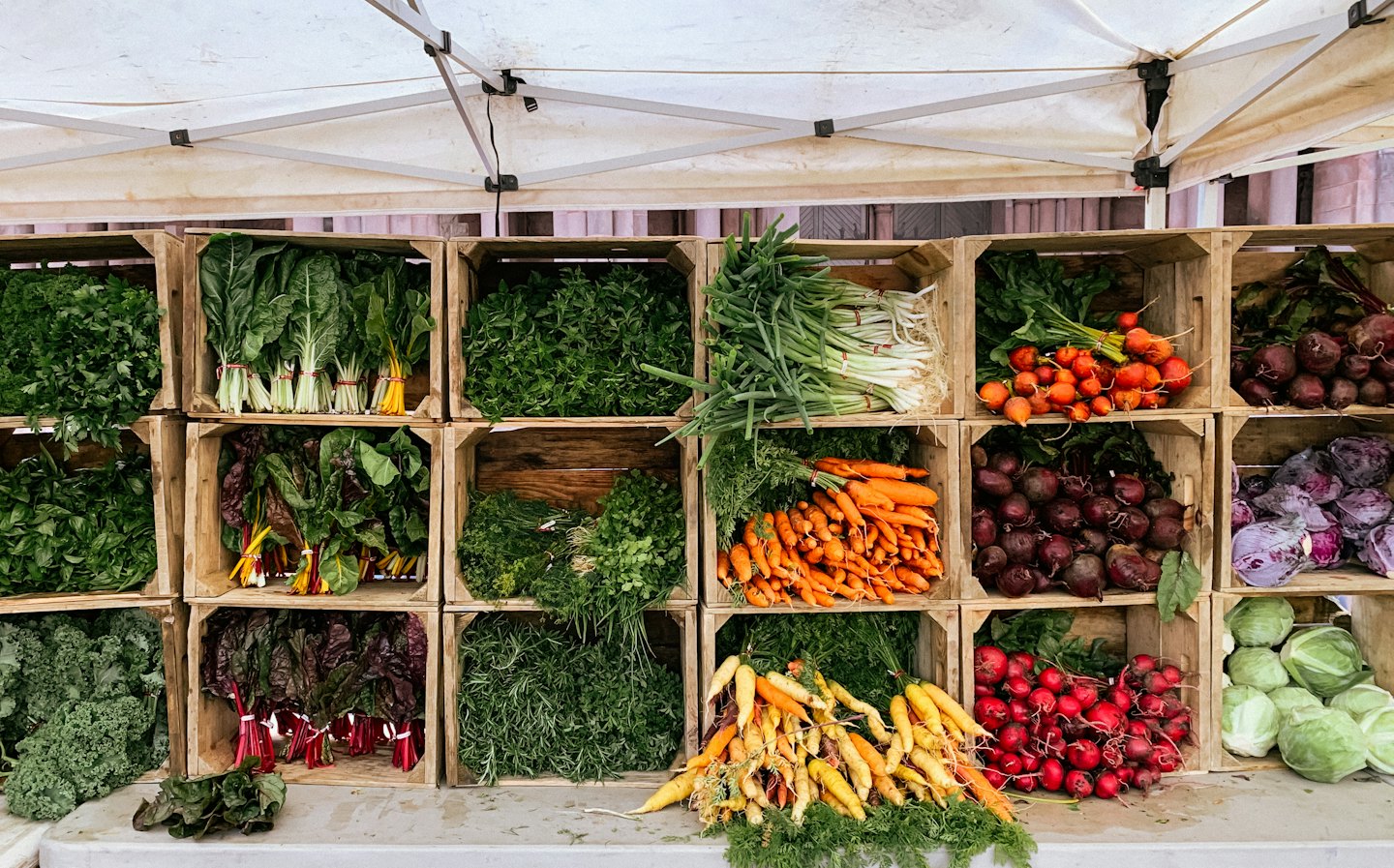Fresh organic vegetables and herbs in wooden crates at a market.