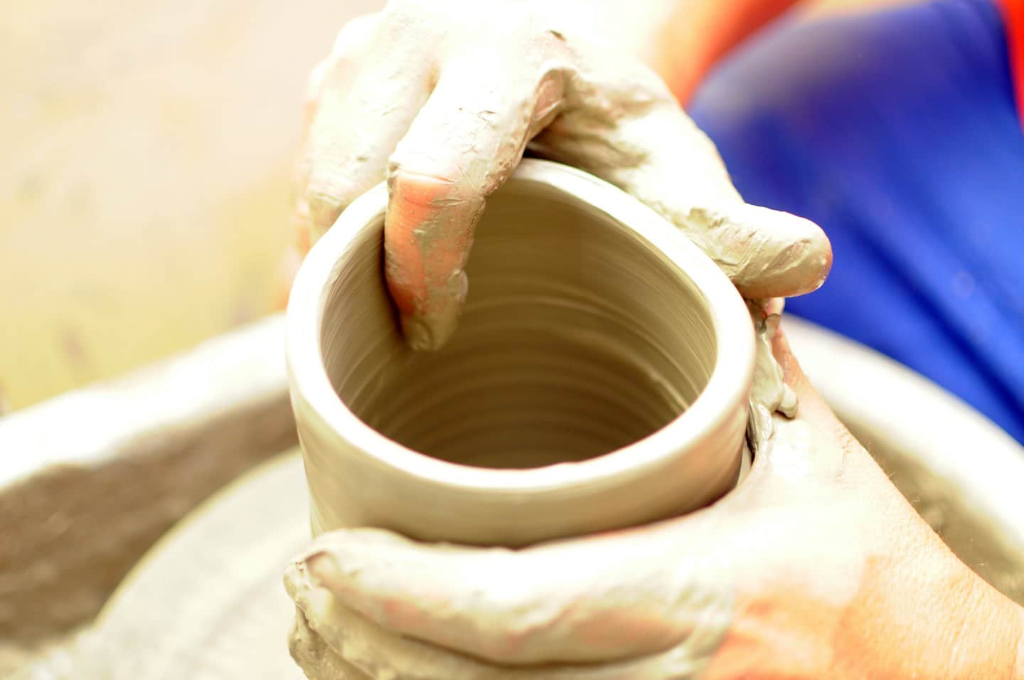 Artisan's hands shaping wet clay on a pottery wheel.